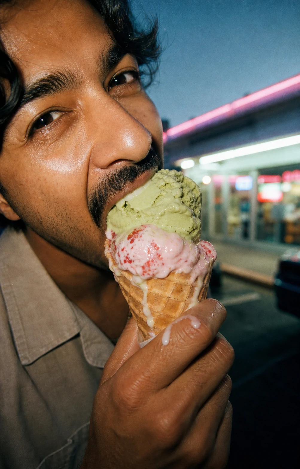 A person eating an ice cream cone at night.